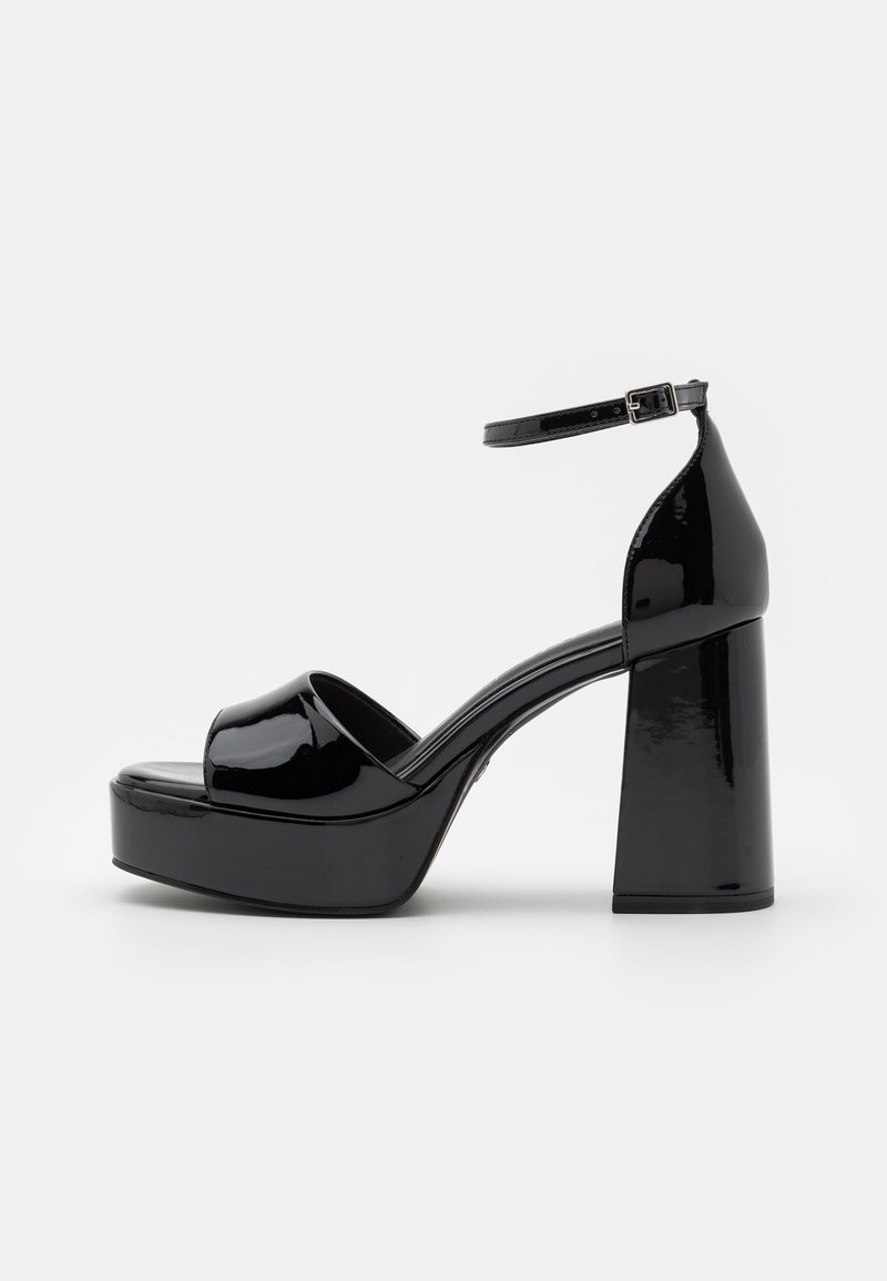 Sandale plateforme en cuir verni noir avec bout ouvert, talon épais bloc, et bride réglable à la cheville avec boucle.