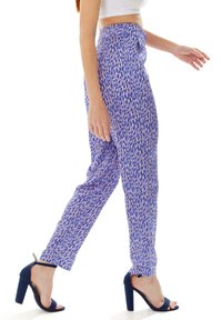 Trousers in blue with a patterned design featuring pink and white accents. Fitted cut with a high waist and worn with navy high heels.