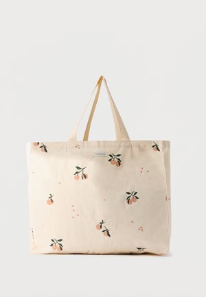 Flødetaske med korte håndtag, dekoreret med små orange frugter og grønne bladmønstre spredt over dens overflade.