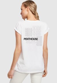 Balta medvilninė marškinėliai su juodu užrašu „PENTHOUSE“ ant nugaros, apsuptu kartojamo šviesiai pilko teksto skirtingomis skaidrumo lygiais.