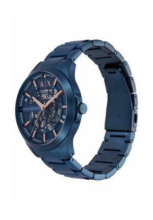 Kék fémes automata Armani Exchange karóra csontváz számlappal, rózsaarany órajelzésekkel és fém kapcsolódó karkötővel.