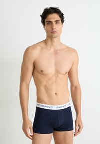 Navyblaue Baumwollboxershorts mit einem weißen elastischen Bund, der das "GANT"-Logo in Schwarz rundum an der Oberseite aufgedruckt hat.