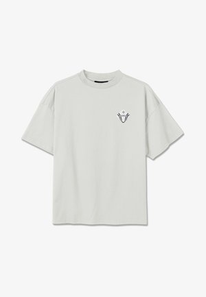 Šviesiai pilkas laisvo stiliaus marškinėliai trumpomis rankovėmis su mažu juodai baltu geometriniu logotipu kairėje krūtinės pusėje.