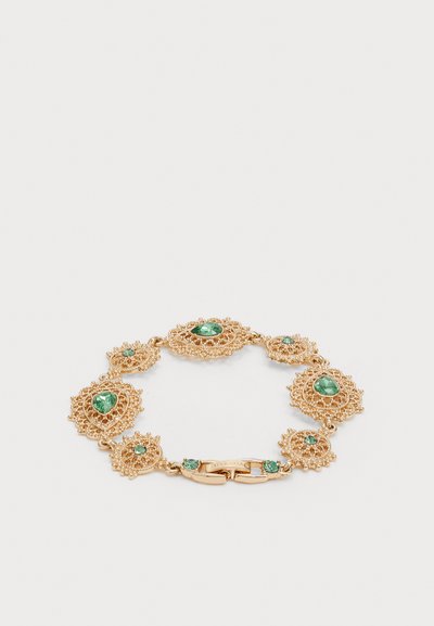 Pulsera en tono dorado con un intrincado diseño similar al encaje. Presenta múltiples piedras preciosas verdes engastadas en eslabones decorativos. Cierre de langosta.