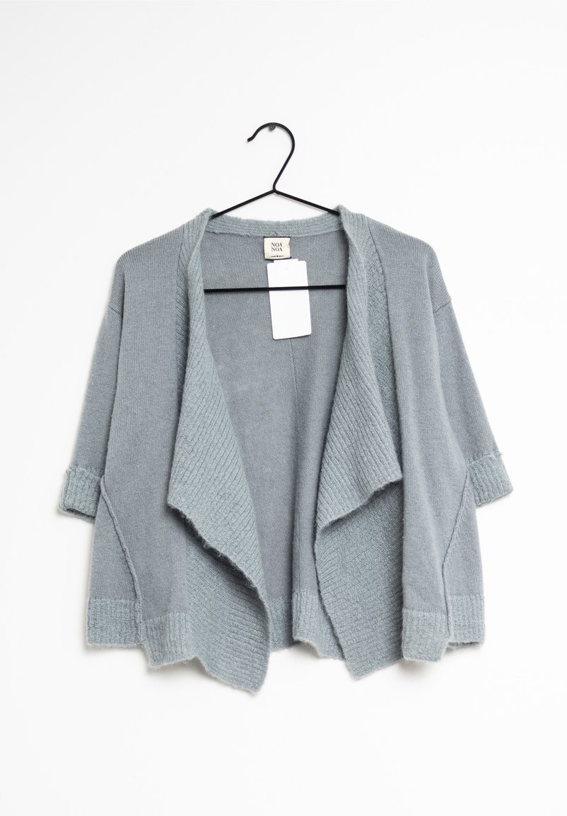 Cardigan tricoté gris clair à ouverture devant, avec de larges revers et des manches trois-quarts, suspendu sur un cintre noir avec une étiquette blanche vierge.