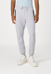 Light gray joggers made of soft cotton blend, featuring zippered pockets, ribbed cuffs, and a drawstring waist. Smooth texture with sporty design.
