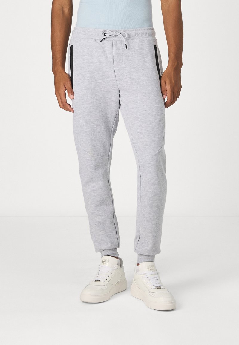 Light gray joggers made of soft cotton blend, featuring zippered pockets, ribbed cuffs, and a drawstring waist. Smooth texture with sporty design.