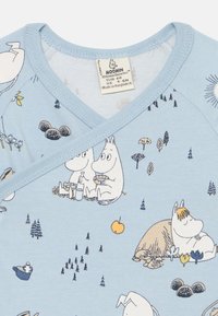 Vestitino in cotone azzurro chiaro con scollo a V, decorato con i personaggi dei Moomin in varie pose tra alberi e fiori. Tessuto lavabile in lavatrice.