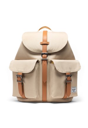 Beżowy plecak z płótna z paskami i klamrami z jasnobrązowej skóry, dwoma przednimi kieszeniami, górnym uchwytem oraz małą metką marki na dolnej prawej kieszeni.
