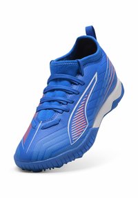 Blaue Sportschuhe mit einem Obermaterial aus strukturiertem Stoff, Gummisohle, einzigartigen Linien und Mustern in Rot und Weiß sowie einer Zuglasche an der Ferse.