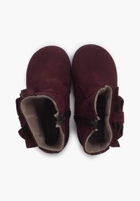 Botas de tobillo de ante burdeos con un suave forro interior, cremalleras laterales y un lazo decorativo en el lado exterior.