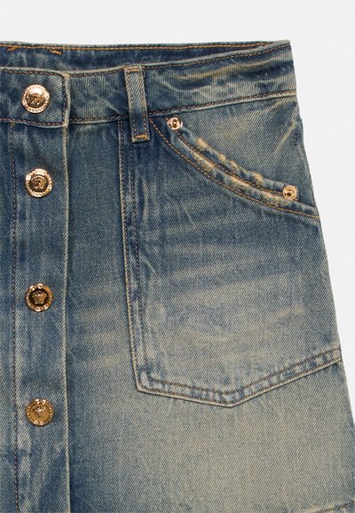 Μπροστινή όψη φθαρμένης μπλε τζιν φούστας με πέντε χρυσά διακοσμητικά κουμπιά και ραμμένη μπροστινή τσέπη με καρφιά.