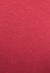 Κόκκινο ύφασμα με ομαλή, λεπτή υφή, που διαθέτει συνεπή, ελαφρώς υφασμένο μοτίβο. Χωρίς ορατές λεπτομέρειες ή εξαρτήματα.