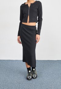 Svart ribbat tvådelat set som består av en kort zip-up topp och en midjehögt kjol. Bärs med svarta och grå sneakers med neondetaljer.