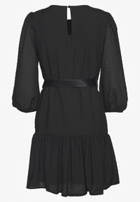 Svart klänning i lätt, texturerad tyg med puffärmar, figursydd midja och utsvängd fåll. Urtagning i ryggen med knappstängning.