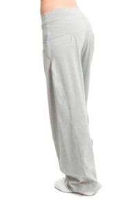 Light gray, loose-fitting pants made of soft fabric, featuring a wide elastic waistband and smooth texture. White footwear visible below.