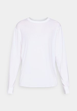 T-shirt blanc à manches longues en coton, avec un col rond, des fentes sur les côtés et des poignets côtelés. Texture lisse avec une coupe régulière.