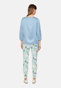 Light blue satin top with three-quarter sleeves paired with patterned fitted pants in pastel green, blue, and black geometric designs.