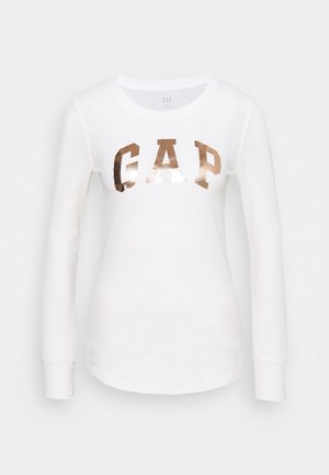 White long-sleeve ribbed shirt with crew neck and metallic copper "GAP" lettering across the chest.