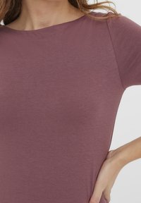 Dámské tričko s krátkým rukávem v burgundské barvě, vyrobené z měkké, lehké tkaniny. Má kulatý výstřih a hladký povrch s minimem švů.