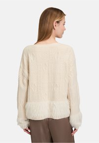 Cremfarbener Pullover mit strukturierten Mustern, einem weichen Kunstfellbesatz am Saum und an den Bündchen sowie einem lässigen Schnitt.
