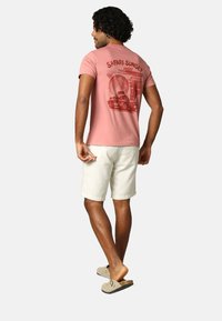 T-shirt en coton rose avec le imprimé "SAFARI SUNSET" présentant une illustration de coucher de soleil et un design de véhicule au dos. Coupe décontractée, manches courtes.