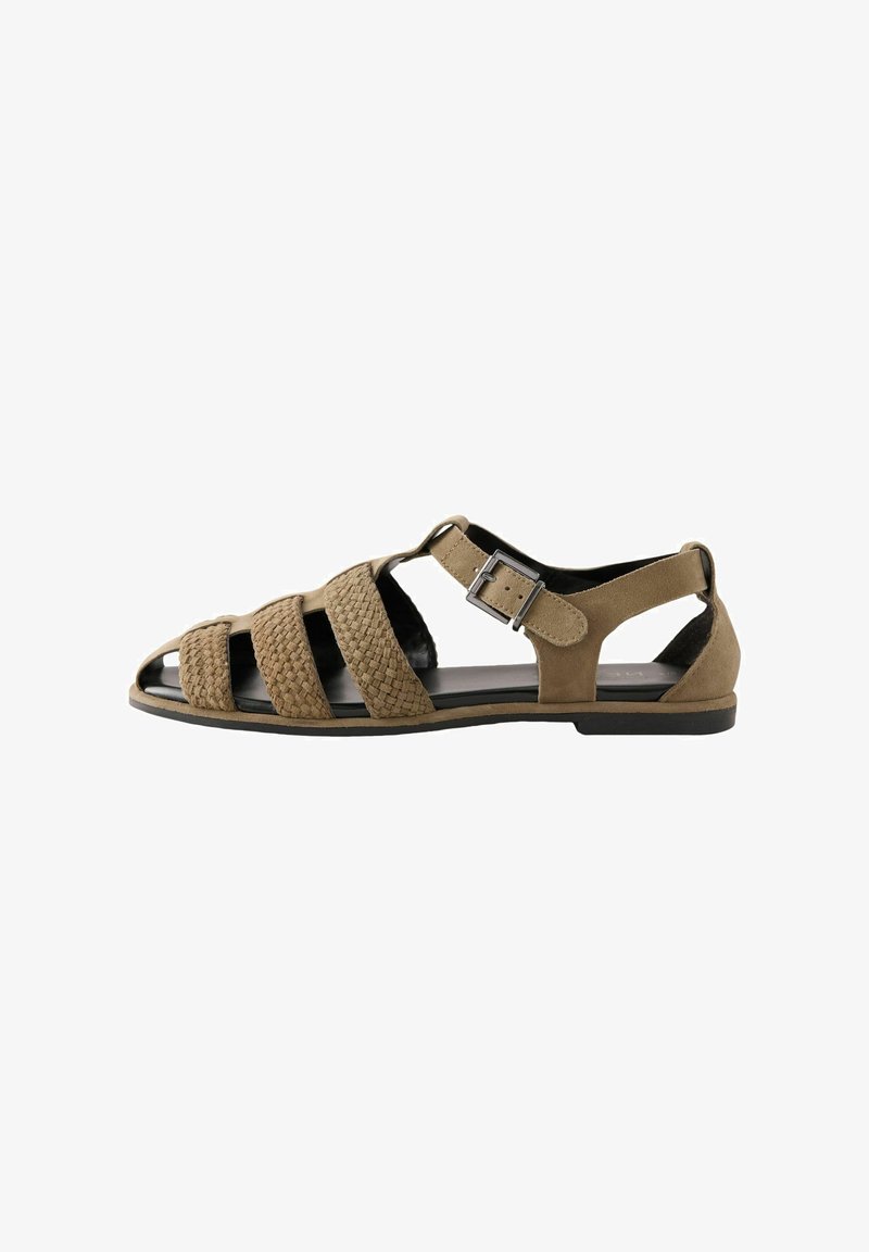 Brown suede sandal with woven straps, open toe and heel, adjustable buckle closure, flat sole, and textured detailing on the straps.