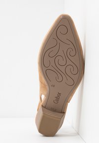 Semelle d'une chaussure femme en daim beige avec des volutes décoratives, talon bloc, taille 4½, marquage de la marque "Gabor" fabriquée au Portugal.