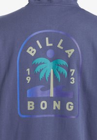 Sudadera morada con un gráfico que presenta una palmera, olas y el texto "BILLABONG", destacado en tonos de azul claro y oscuro.
