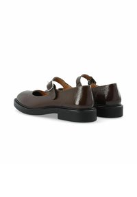 Ein Paar dunkelbraune Lackleder-Mary-Jane-Schuhe mit silbernen Schnallenriemen und dicken schwarzen Sohlen, von hinten und von der Seite gezeigt.