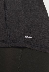 Svart atletisk skjorta med en texturerad yta. Har en sydd fåll och en "DRYCELL"-etikett i vitt. Matchas med svarta leggings.