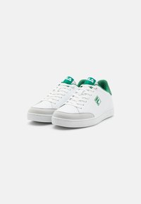Baltas sneakers ar zaļiem akcentiem un logo, ar gludu ādas virsu, mīkstu apkakli un pelēku zamšādas purngalu. Klasicisks sporta dizains.