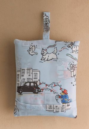 Kis szövetzsák hurokkal, rajzfilm kutyákkal, madarakkal, fekete taxival, épületekkel és egy figurával, aki piros sárkányt reptet, nyomtatva.