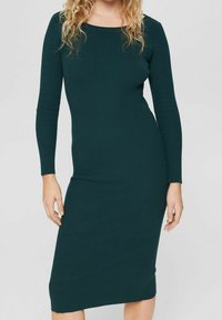 Robe en maille côtelée vert foncé avec manches longues, encolure bateau, et silhouette ajustée, arrivant sous le genou avec une texture lisse.