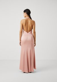 Long, backless gown in soft pink satin with a halter neck and fitted silhouette, featuring a discreet zipper closure.