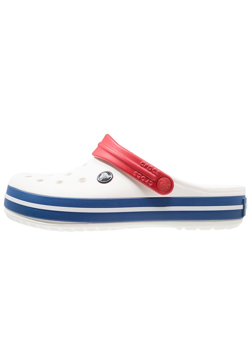 Tamanco branco com tira vermelha e sola azul, apresentando buracos de drenagem e um logótipo circular. Textura suave com salto baixo e bico arredondado.