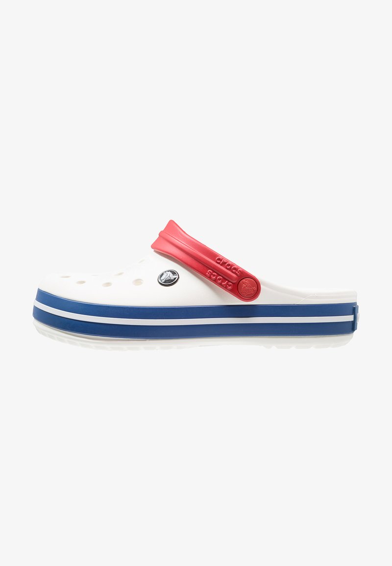 Tamanco branco com tira vermelha e sola azul, apresentando buracos de drenagem e um logótipo circular. Textura suave com salto baixo e bico arredondado.