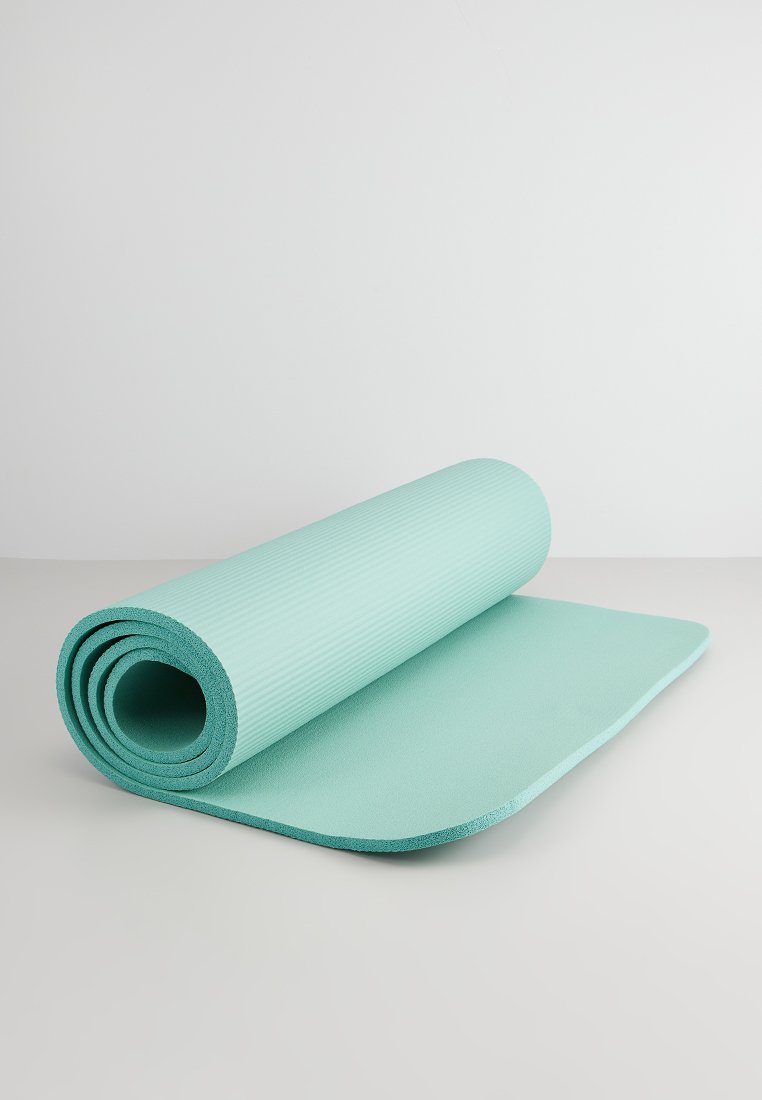 Colchoneta de yoga de color azul claro parcialmente enrollada sobre una superficie plana con fondo blanco liso.