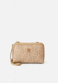 Beige handtas met een gestructureerd geometrisch patroon, hardware in goudkleur, ritssluiting en afneembare band. Voorzien van een logo aan de voorkant.