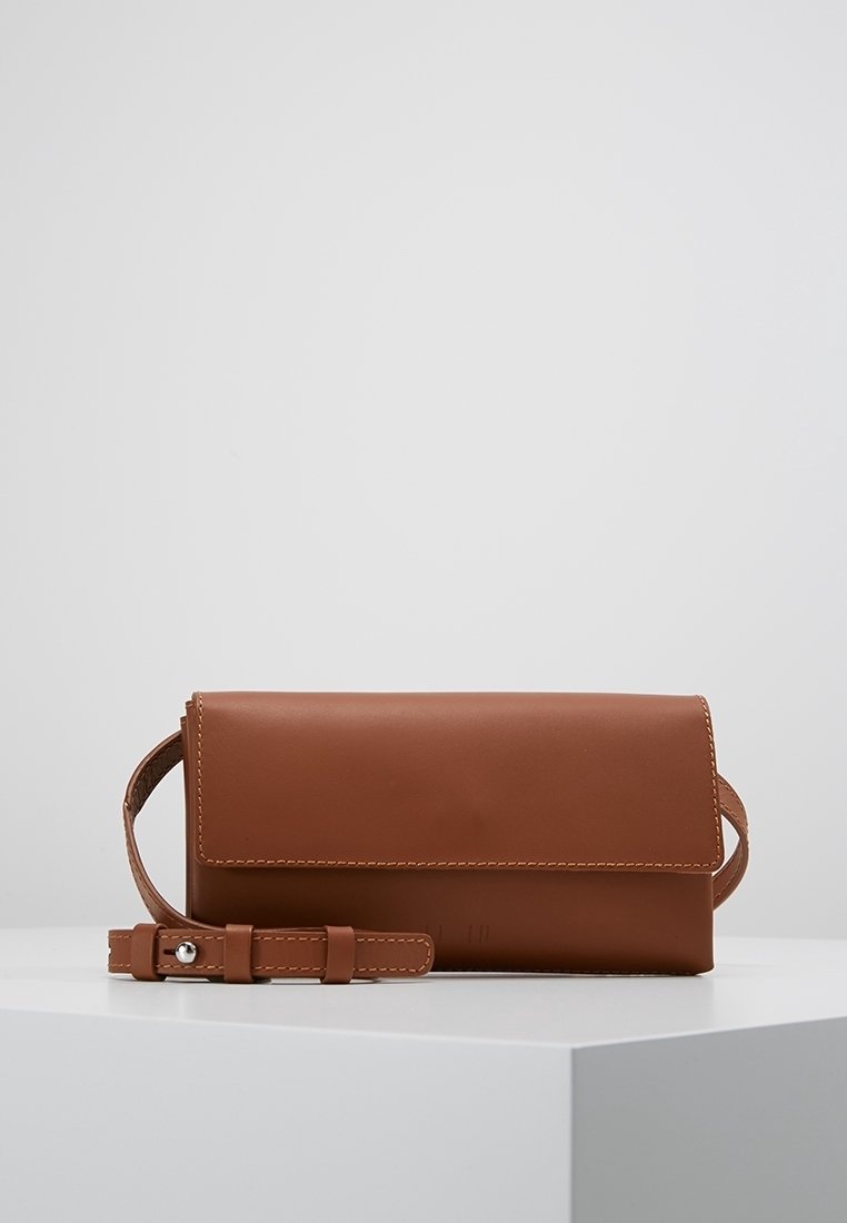 Ruskea nahkainen laukku, jossa on litteä suorakulmainen muoto, vaippakannen ja irrotettava rannetuppi. Sisältää näkyvää ommelta.