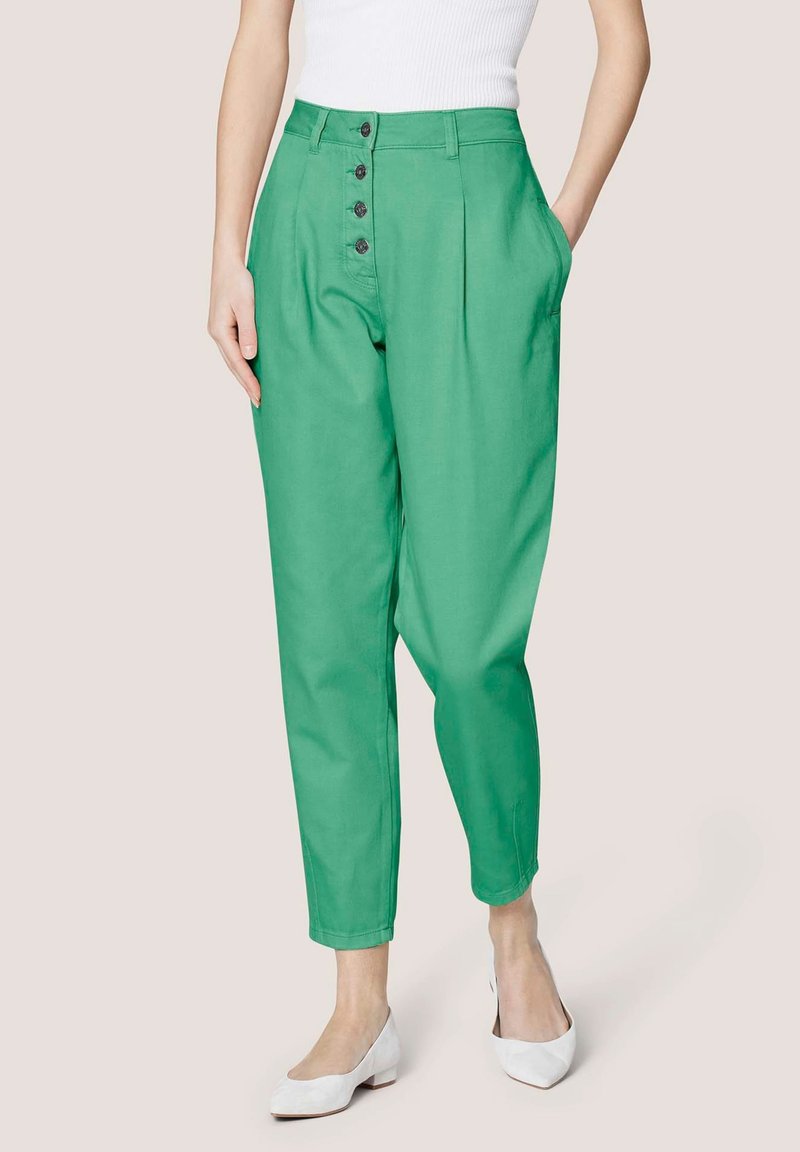 Grüne hoch-taillierte Hose mit Knopfverschluss, seitlichen Taschen und schmal zulaufendem Bein. Aus einem glatten Stoff gefertigt. Mit grauen Knöpfen akzentuiert.