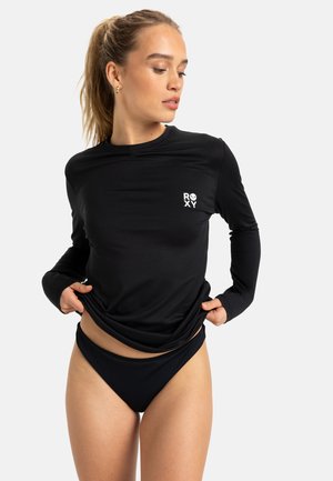 Pitkähihaainen musta uimapaita, jossa on Roxy-logo rinnassa, yhdistettynä yhteen sopiviin mustiin ribbattuihin bikinitaskuihin, joissa on klassinen istuvuus.