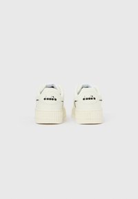 Λευκά αθλητικά παπούτσια με ανυψωμένη σόλα, λείο υφή και μαύρο λογότυπο στη φτέρνα· σχεδιασμένα με μαλακό πέλμα για άνεση.