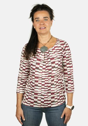 Top de manga larga con un patrón geométrico en burdeos, rosa y beige sobre un fondo claro. Cuello redondo con detalle de fruncido.