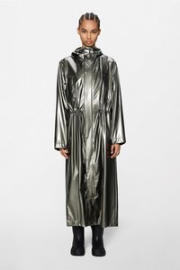 Μεταλλικό χακί πράσινο αδιάβροχο με κουκούλα, εφαρμοστό στη μέση, μακριά μανίκια και πλαϊνές τσέπες, φορεμένο πάνω από μαύρες λαστιχένιες μπότες. Με λεία υφή.