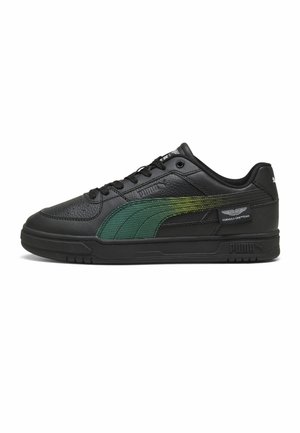 Baskets noires avec bande Puma à dégradé vert, étiquette Aston Martin Formula One Team, design bas, tige en cuir texturé, semelle noire.