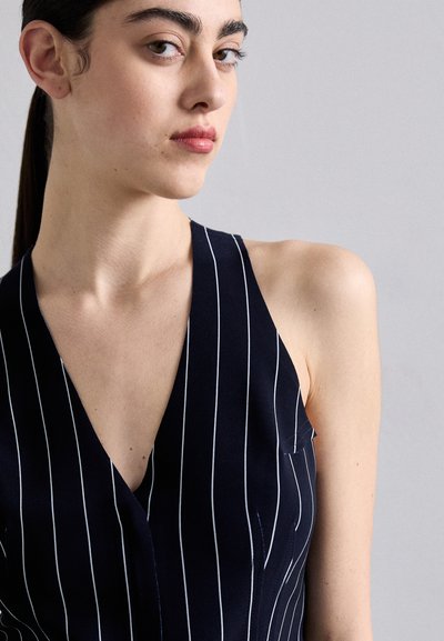 Navy sleeveless top with white vertical stripes, featuring a deep V-neck design and a small pocket on the left side. Soft fabric texture.