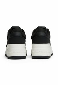 Sneaker nere con una toma superiore testurizzata, suola spessa bianca e nera e un logo del marchio sul tallone. Tab di supporto rinforzato.