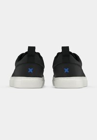 Μαύρα αθλητικά παπούτσια με λείο φινίρισμα, λευκές λαστιχένιες σόλες και μπλε λεπτομέρειες στη φτέρνα. Διαθέτουν θηλιά για εύκολο φόρεμα.