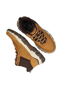 Braune Wildleder- und Mesh-Wanderschuhe mit einer robusten Sohle, Schnürdesign und kontrastierenden cremefarbenen Akzenten. Mit sichtbarem Branding und Textur.